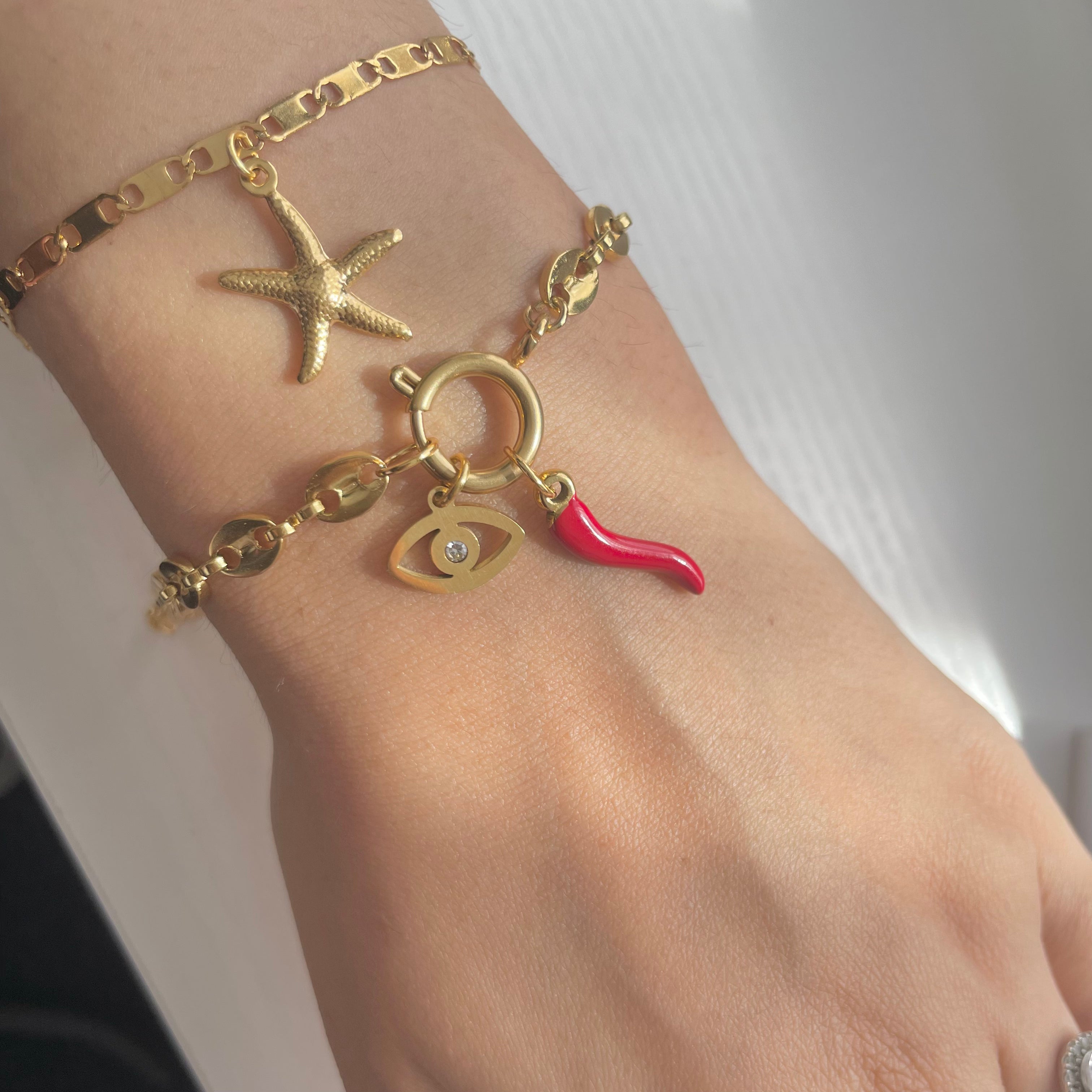 Gold bracelet stack with chilli charm and crystal eye charm