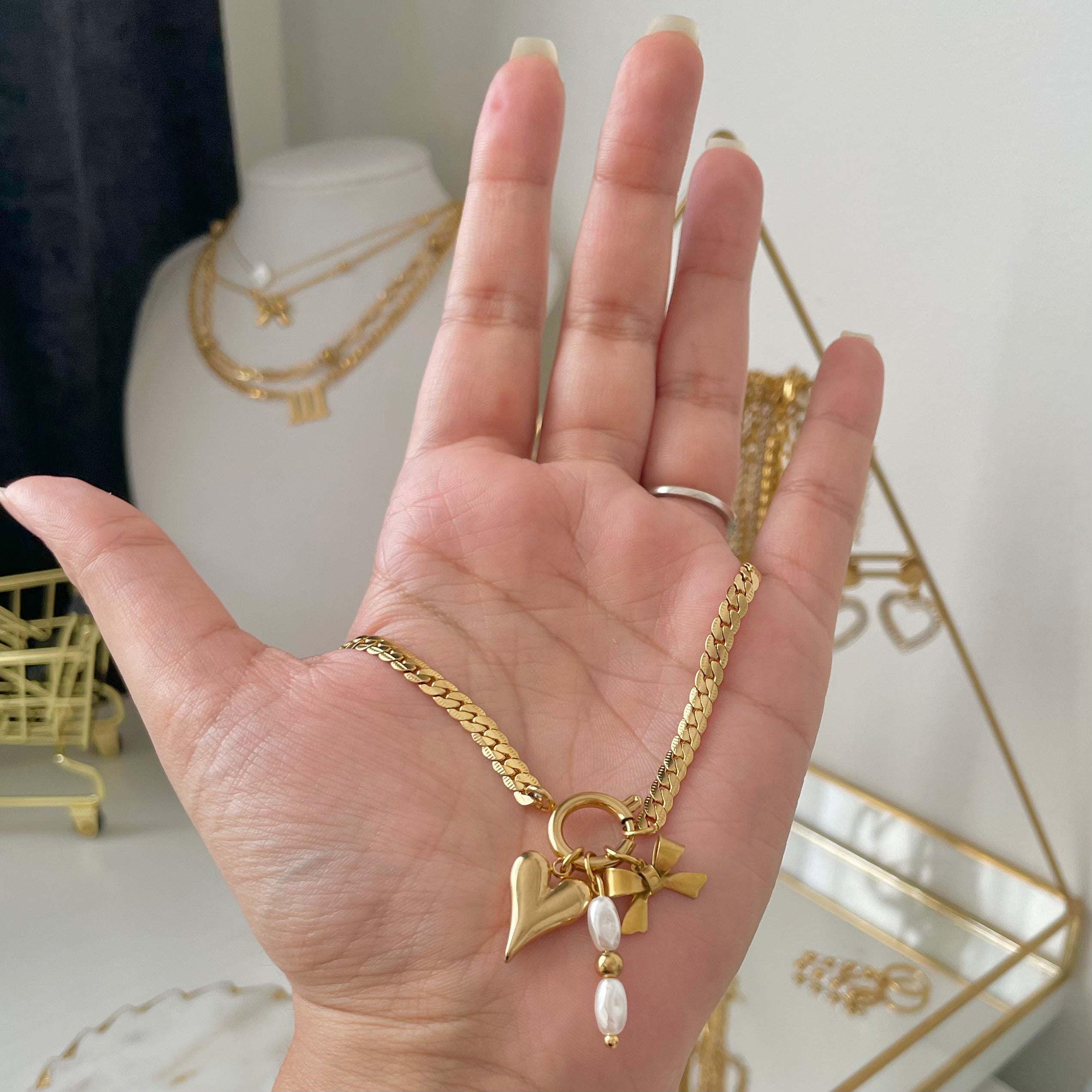 gold charm necklace with heart charm and bow charm and pearl charm