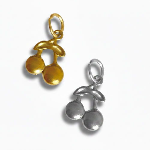 Two charm pendants in the shape of cherries, one in gold color and one in silver color, isolated on a white background.