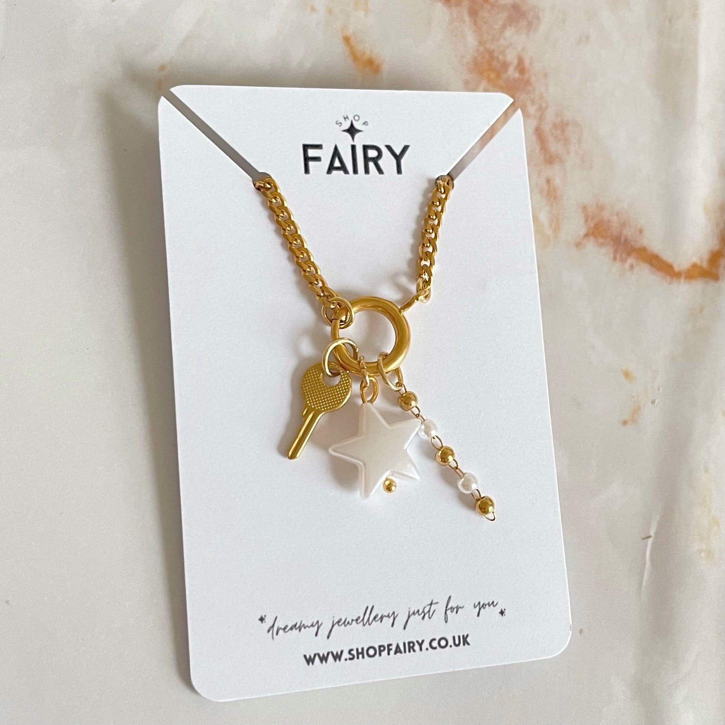 Gold charm necklace with pearl charms and key charm