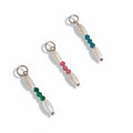 Three pearl and colored bead charms attached to small silver rings, displayed against a white background.