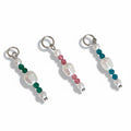 Three pearl drop charms with colored beads in green, blue, and pink, each attached to a small metal ring.