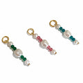 Three pearl drop charms with gold-colored rings and colored beads, jade green, sea blue, and baby pink, displayed against a white background.