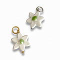 Two white flower-shaped charms with green centers on a white background