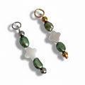 Two olive green pearl charms with a clover shape in the center, accompanied by gold and silver steel beads, displayed against a white background.
