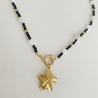 Necklace with a gold flower pendant on a charm necklace