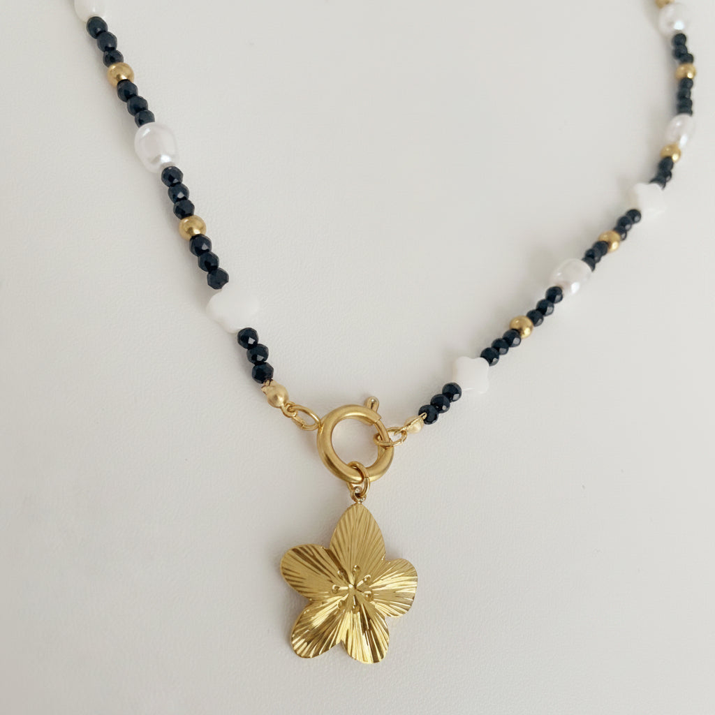 Necklace with a gold flower pendant on a charm necklace