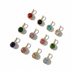 Gold pendants with colorful gemstones on a light background
