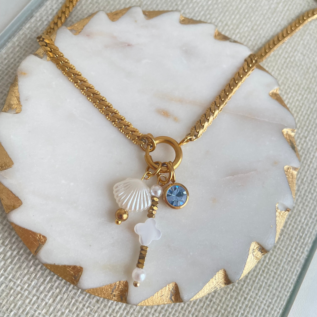 Gold necklace with charms on a marble surface