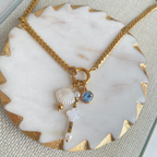 Gold necklace with charms on a marble surface