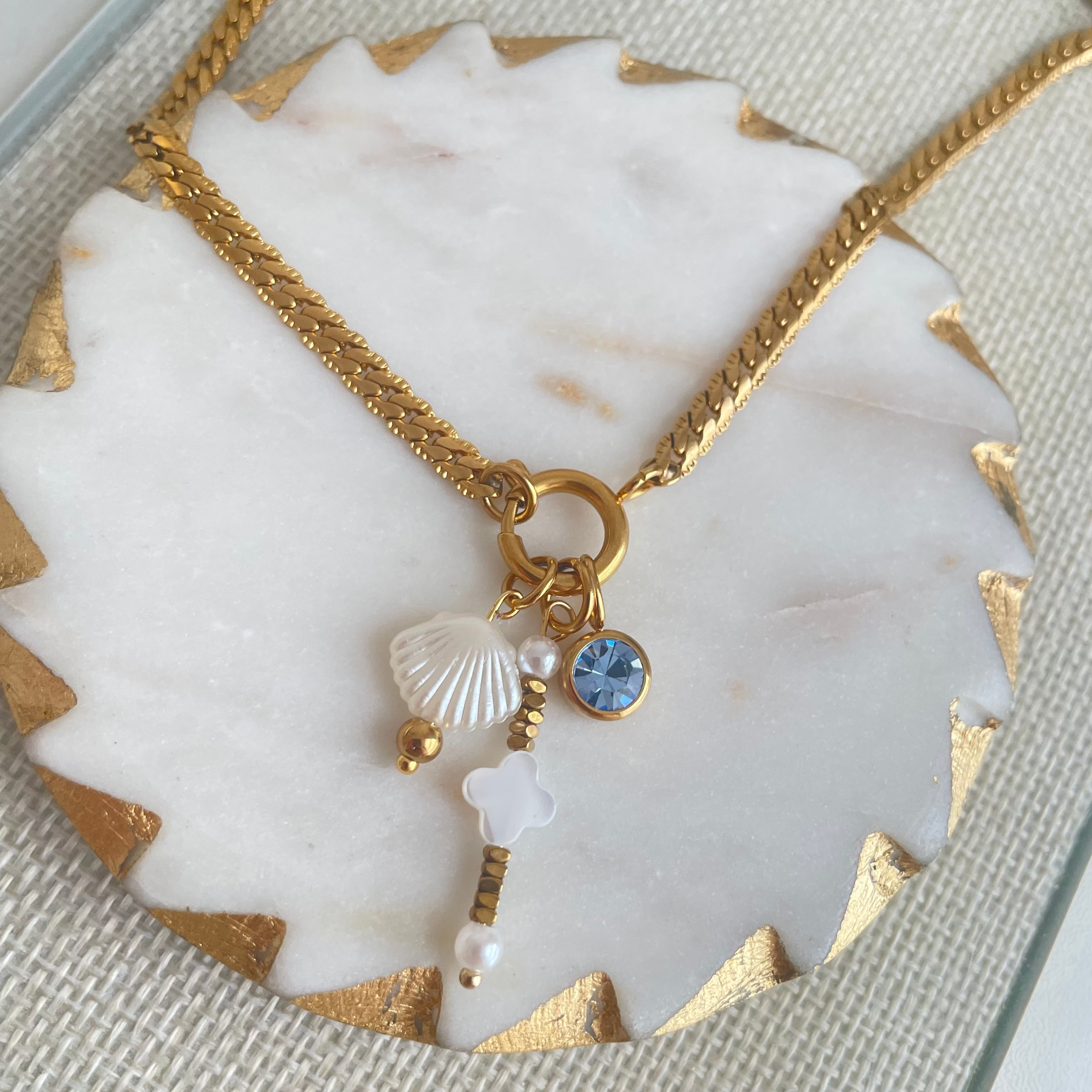 Gold necklace with charms on a marble surface