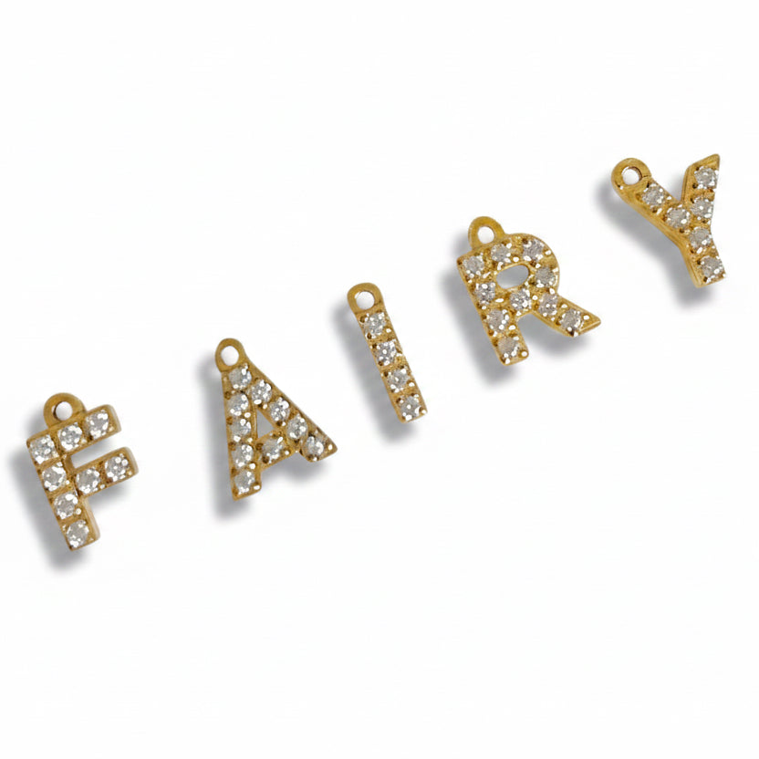 Gold letter charms spelling 'FAIRY' on a white background