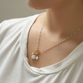 A gold-plated steel chain necklace with white enamel beads and a mermaid charm pendant worn by a person.