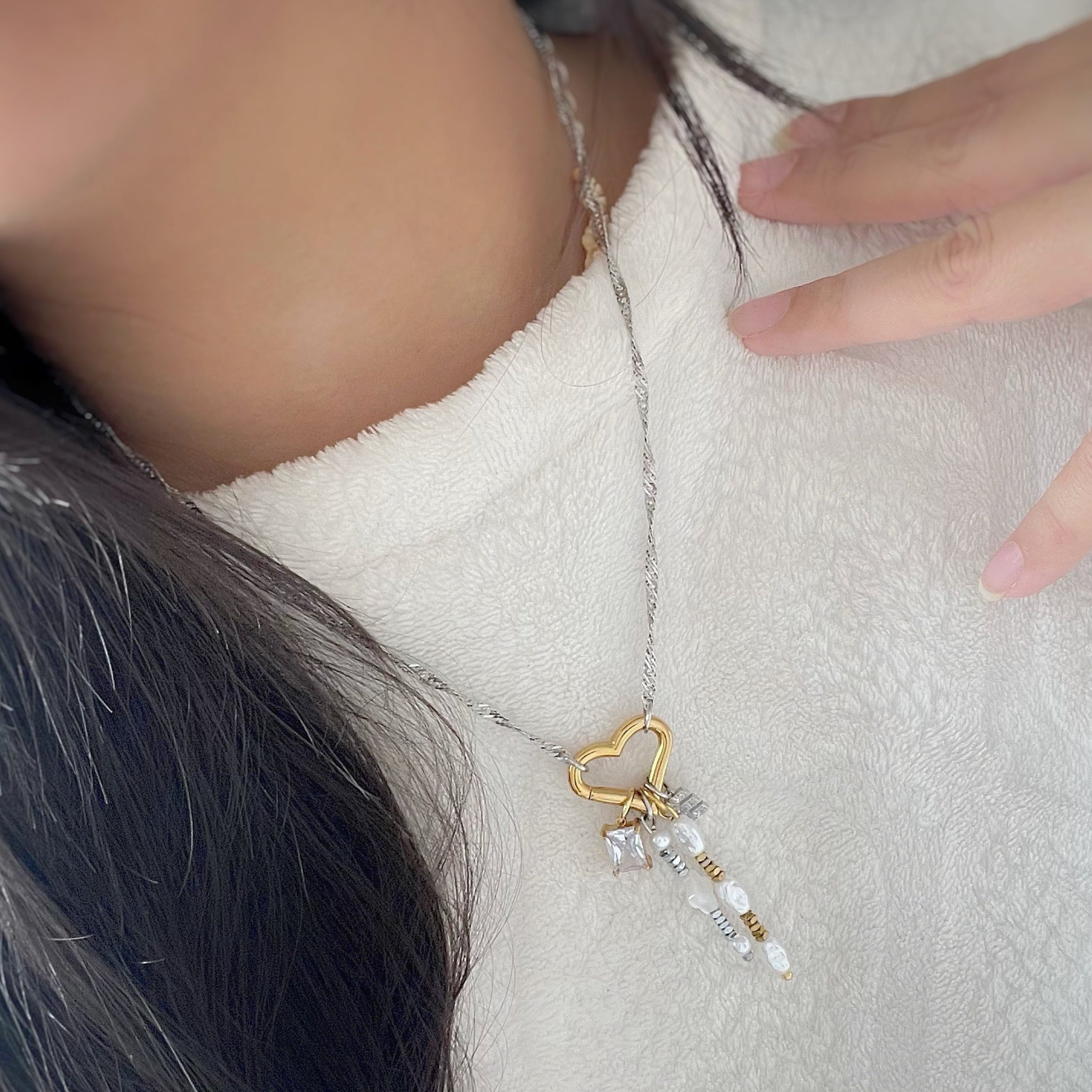 Necklace with a gold heart pendant worn by a person on a white background