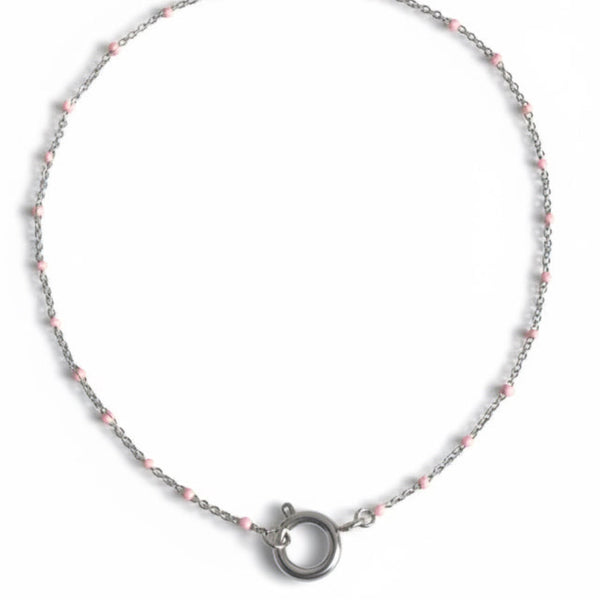 Necklace with pink beads and silver clasp on a light gray background