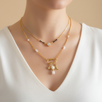 Gold necklace with charms on a person wearing a black and white outfit.
