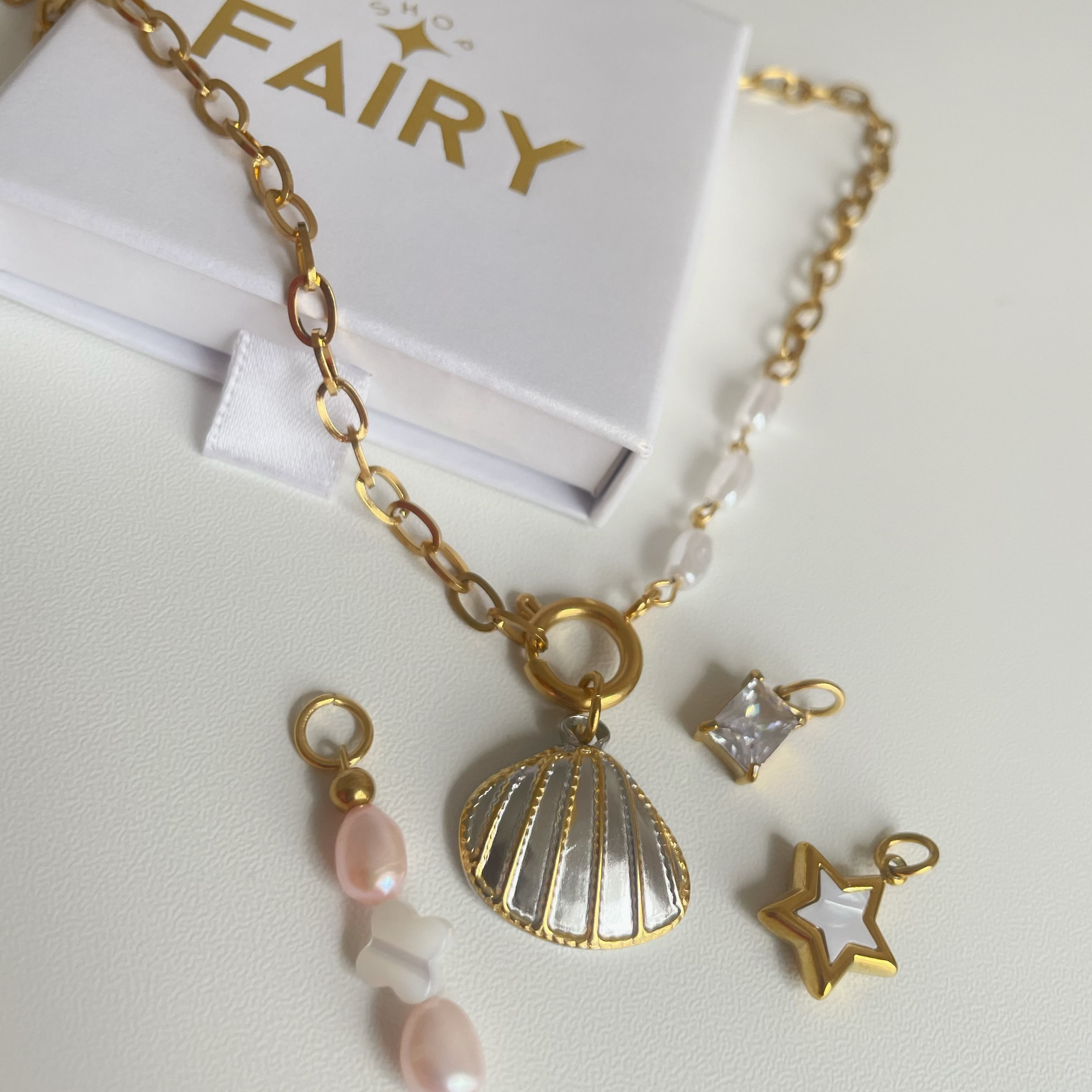 Gold necklace with charms on a white surface