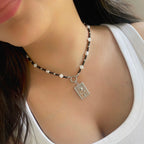 Necklace with a pendant worn by a person, focusing on the necklace and its design.