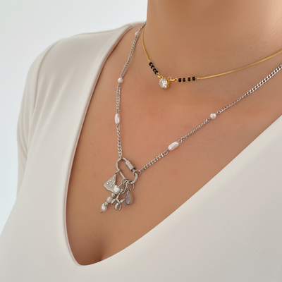 Silver necklace with a heart and butterfly pendant on a person wearing black lace lingerie.