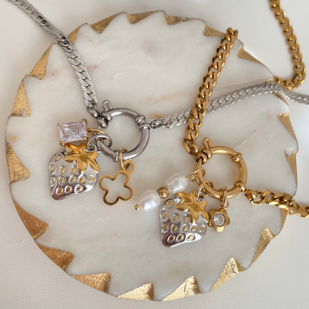 Two necklaces with charms on a decorative stone surface