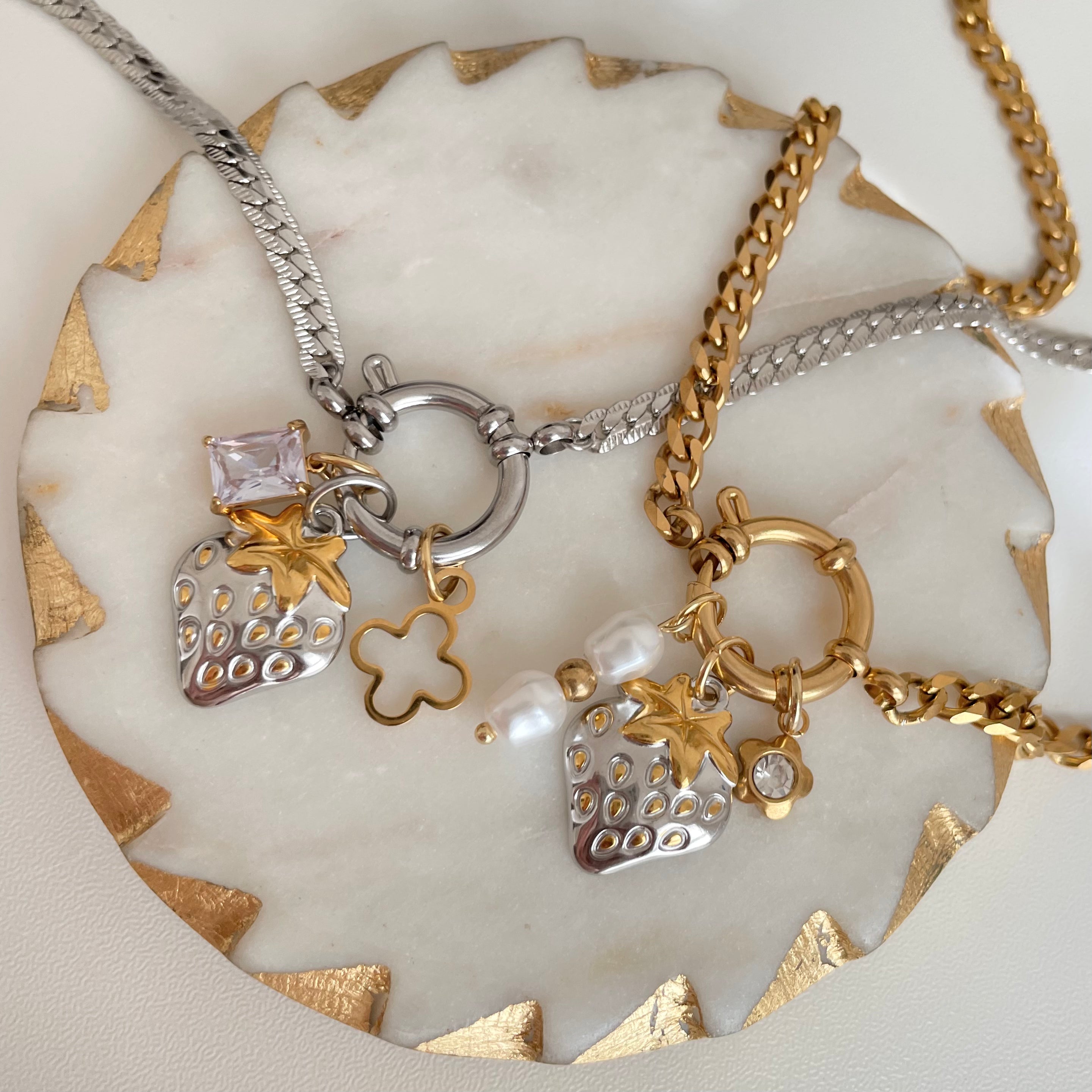 Two necklaces with charms on a decorative stone surface